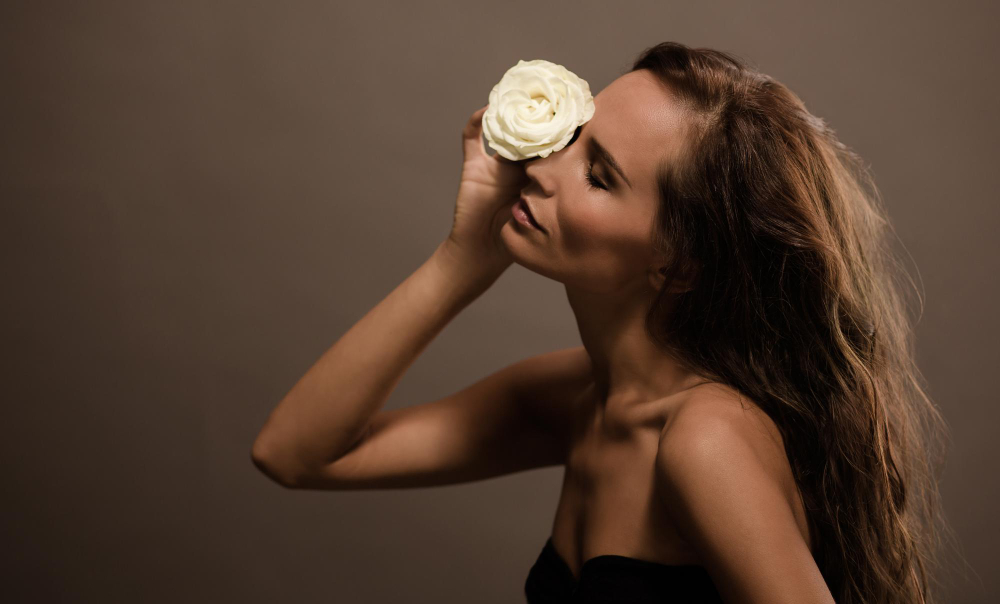 sensual-fashion-model-holding-white-rose-with-her-eyes-closed-lady-with-long-brown-hair-posing-photographer-studio.jpg